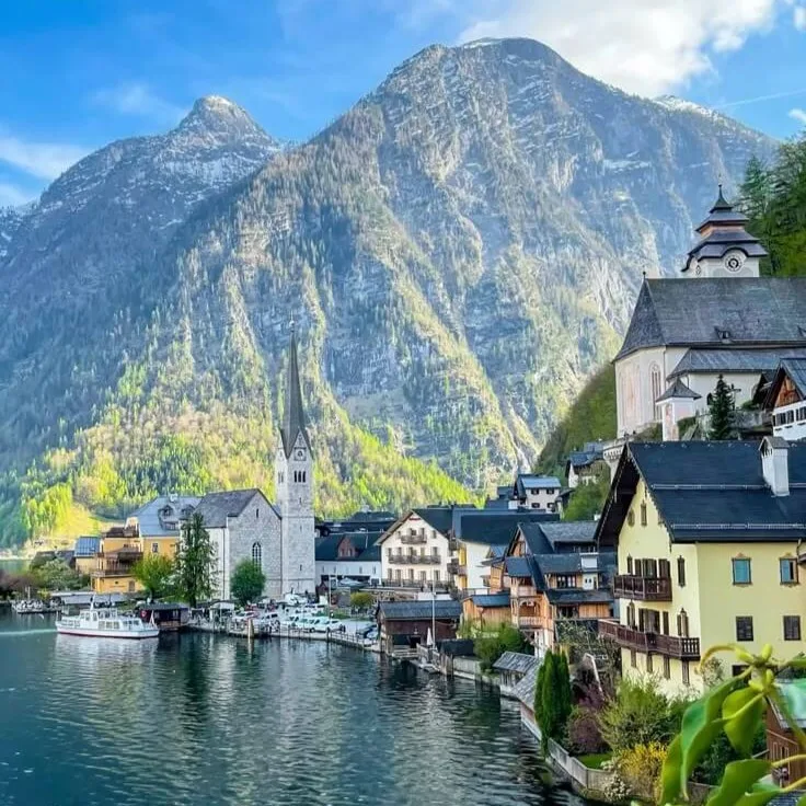 The lakeside village of Hallstatt in Austria, its houses between the water and the steep wooded mountainside.