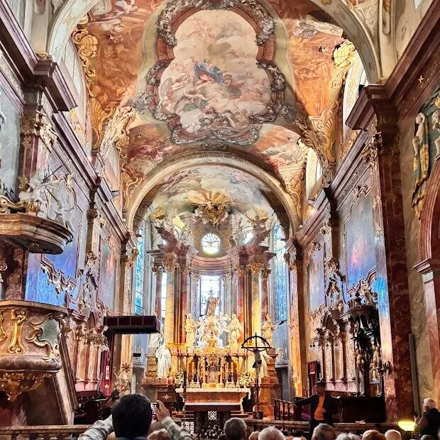 The frescoed baroque interior of a pilgrimage church in Slovakia, looking towards the gilded high altar.