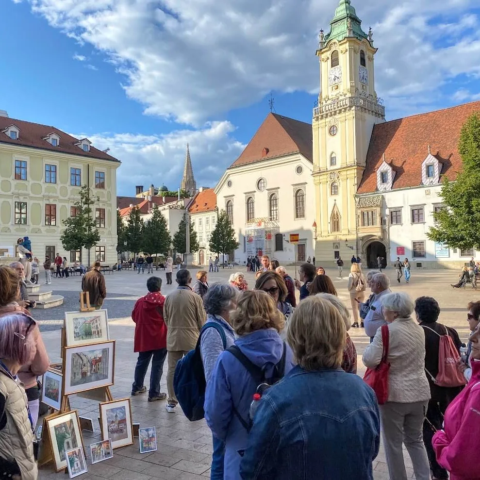 A tour group on the Main Square in Bratislava, in front of the Old Town Hall with its clock tower.