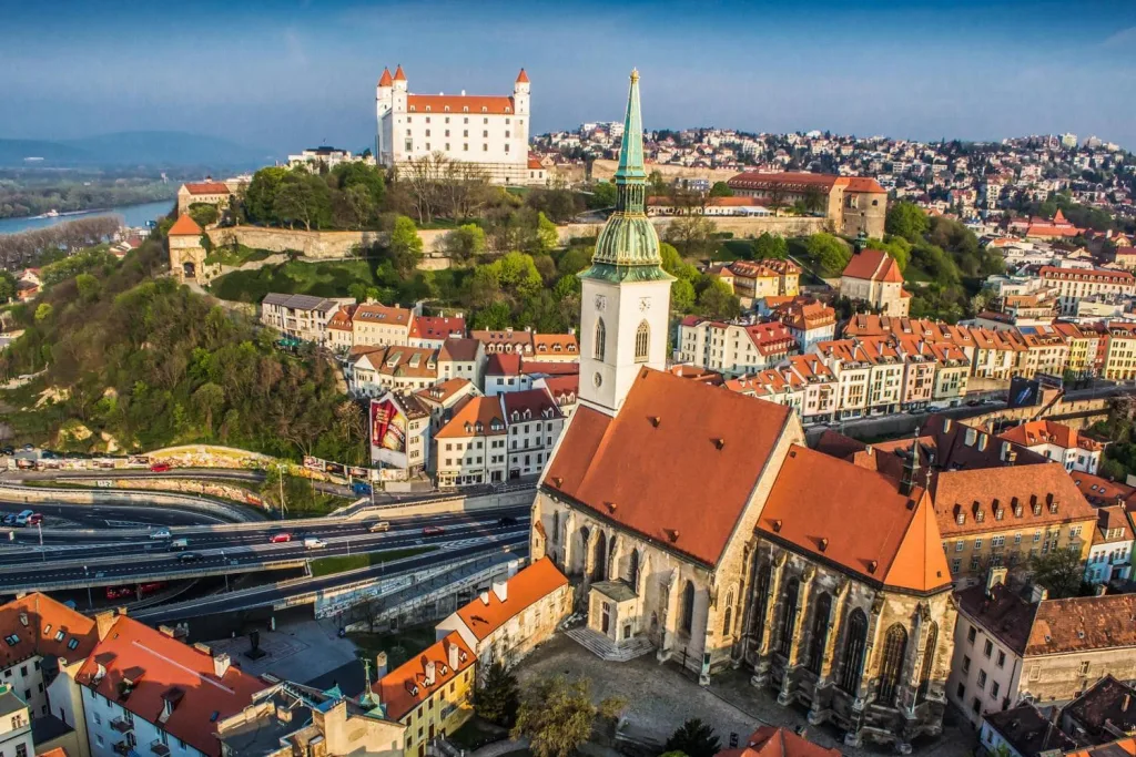 Bratislava’s old town from above, with the red roofs of St Martin’s Cathedral in the foreground and the castle on its hill behind.