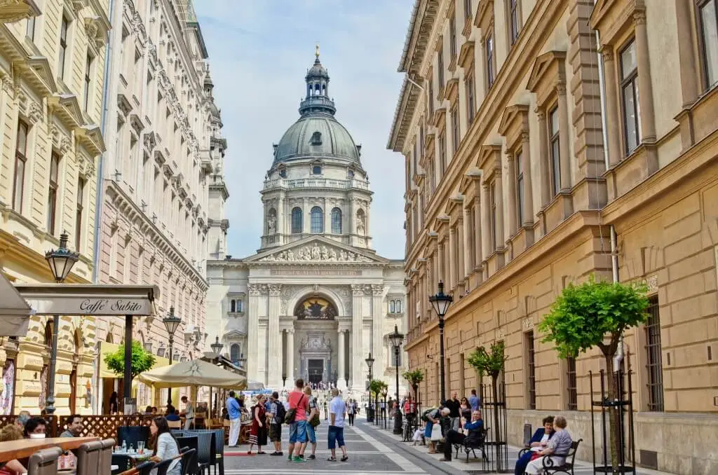 St Stephen's Basilica in Budapest at the end of a pedestrian street lined with cafe terraces.
