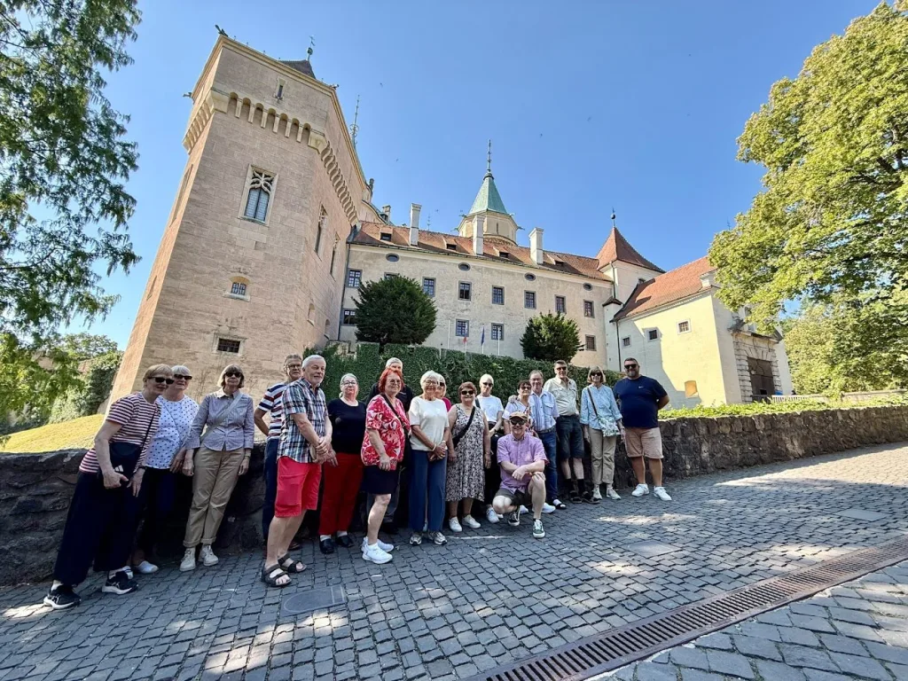 A tour group posed outside Bojnice Castle in Slovakia on a sunny day.