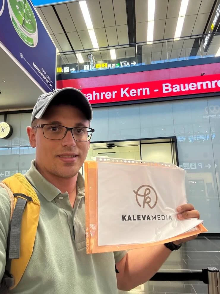 Andrej Stanik holding a name sign to welcome his guests in an airport arrivals hall.