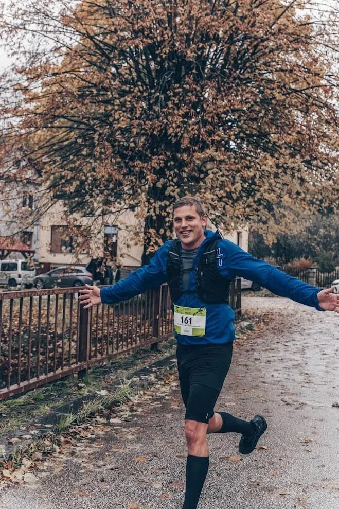 Andrej Stanik running in an autumn race, arms spread wide as he passes the camera.