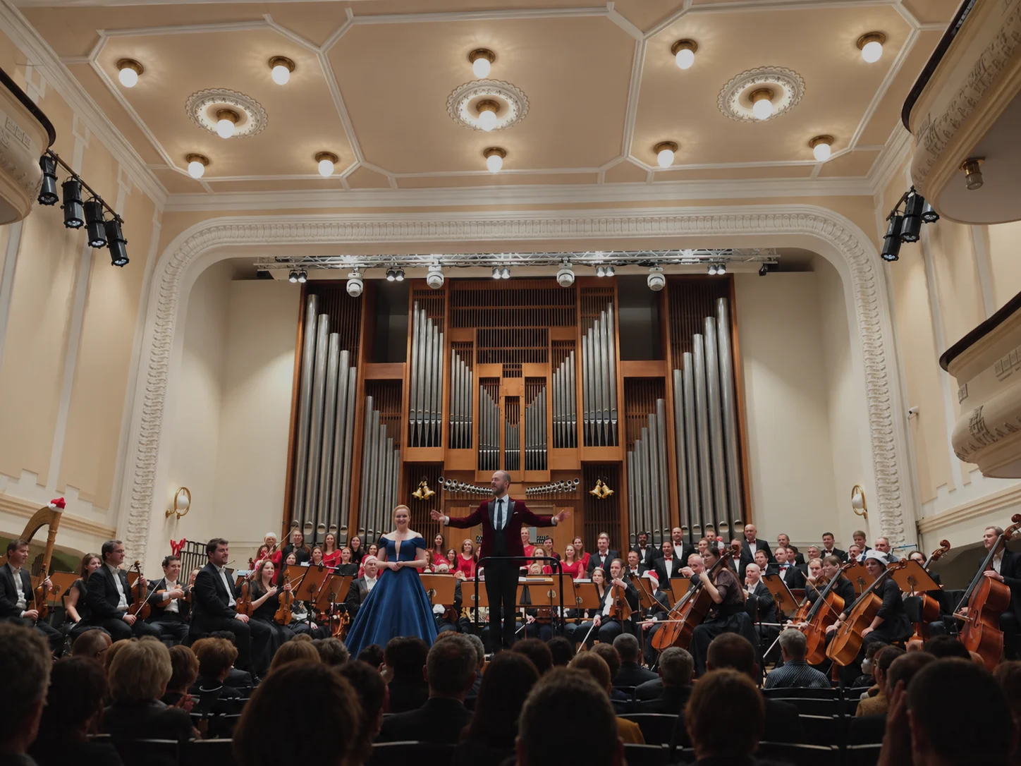 An orchestra, choir and soloist on stage in front of the pipe organ at the Dom umenia Fatra concert hall in Žilina, performing for event guests.