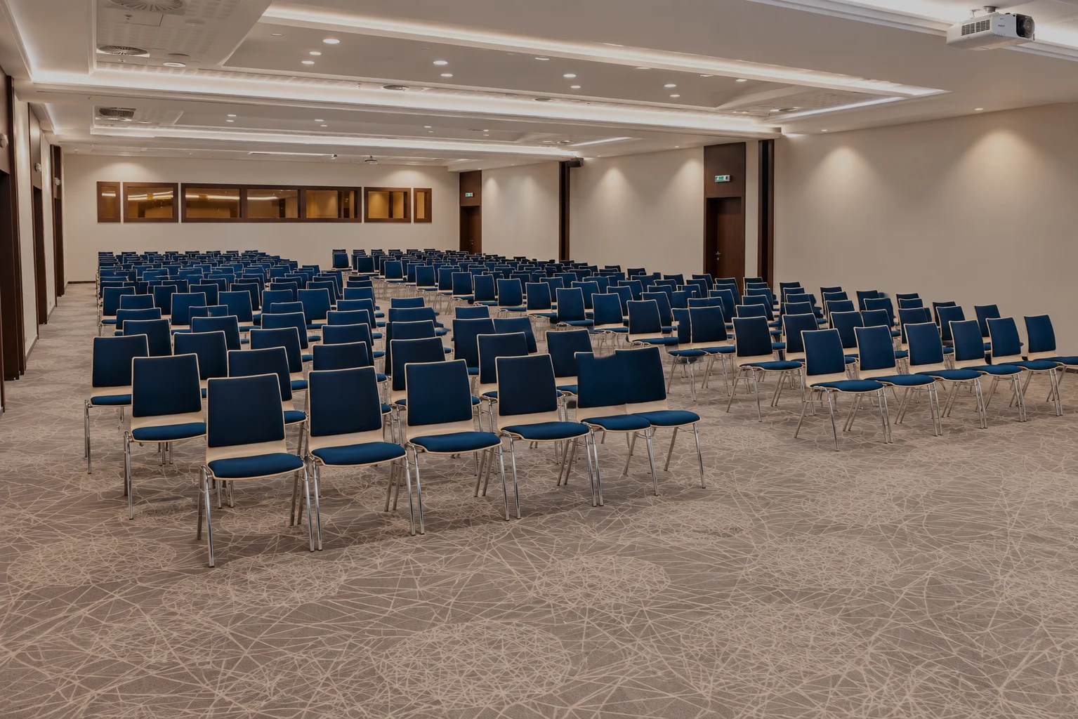 A conference hall set theatre-style with rows of blue chairs, ready for a congress.