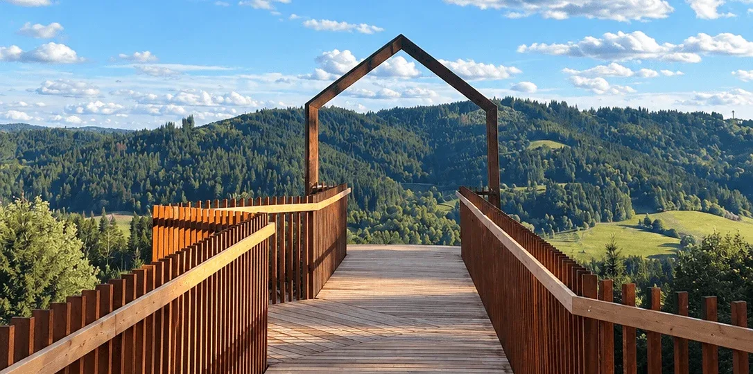 The wooden lookout boardwalk at Korňa in the Kysuce region, its house-shaped frame overlooking forested hills.