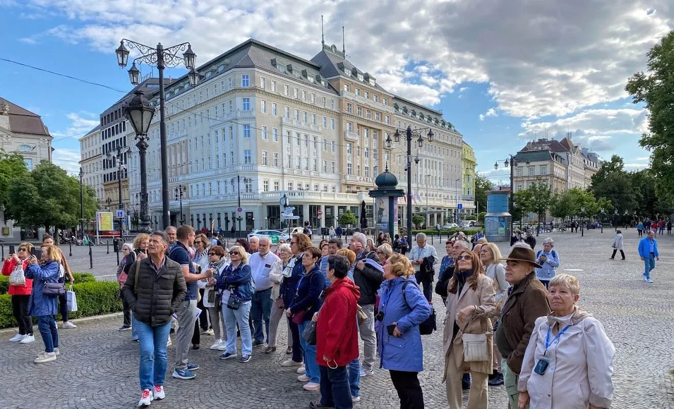 A tour group on Hviezdoslav Square in Bratislava's Old Town, gathered in front of the historic Carlton Hotel.