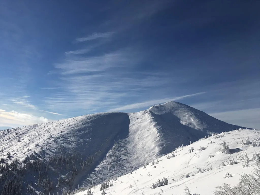 A snow-covered ridge in the Fatra Mountains of Slovakia, with rime-frosted trees and ski tracks across the slope under a clear winter sky.