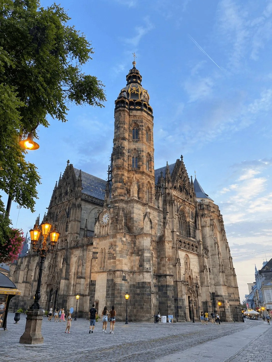 St Elizabeth Cathedral in Košice at dusk, the largest church in Slovakia, with its Gothic tower lit above the main street and lamps burning on the square.