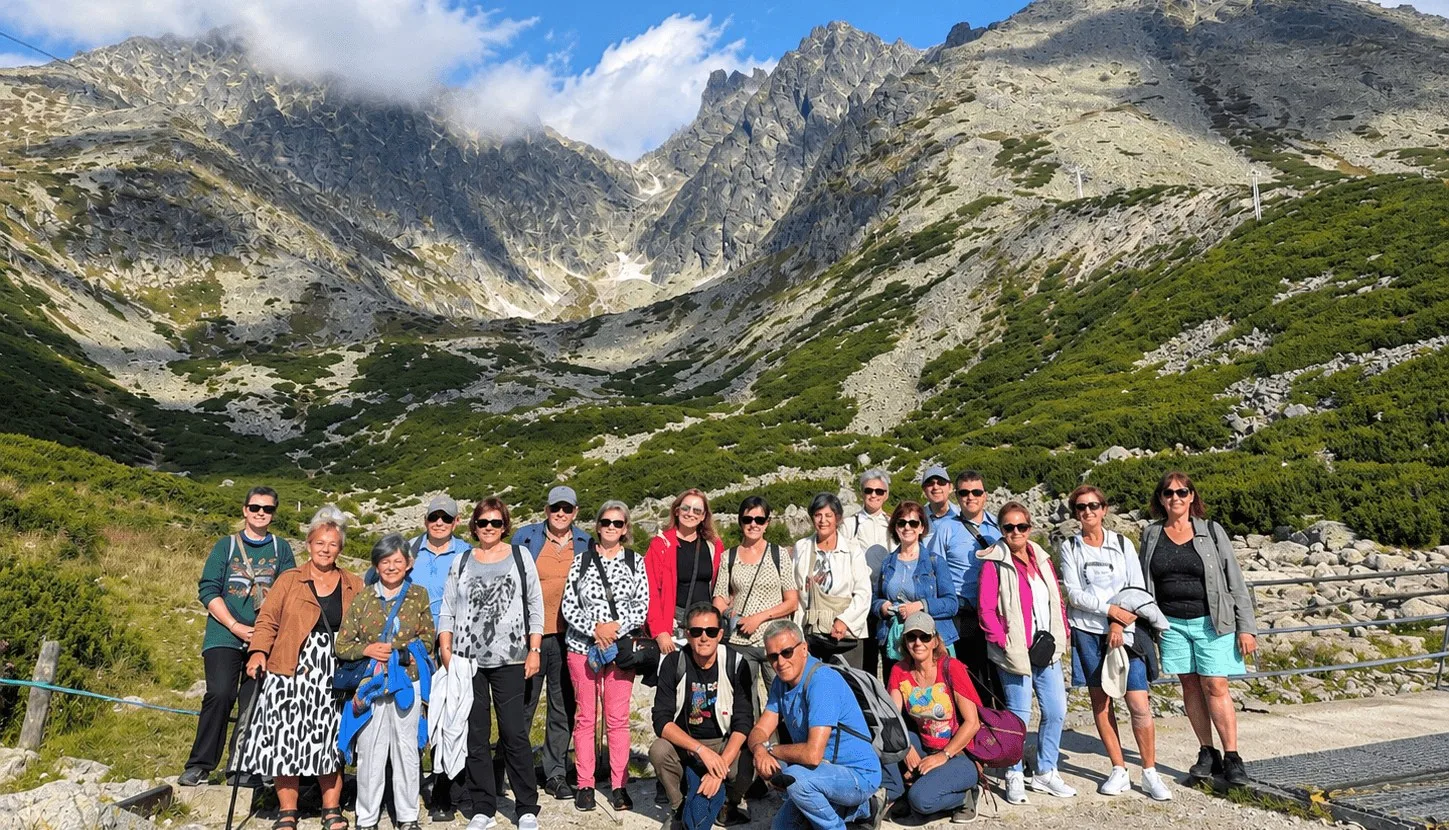 Eine Reisegruppe am Skalnaté pleso in der Hohen Tatra in der Slowakei, mit den felsigen Gipfeln der Tatra dahinter.