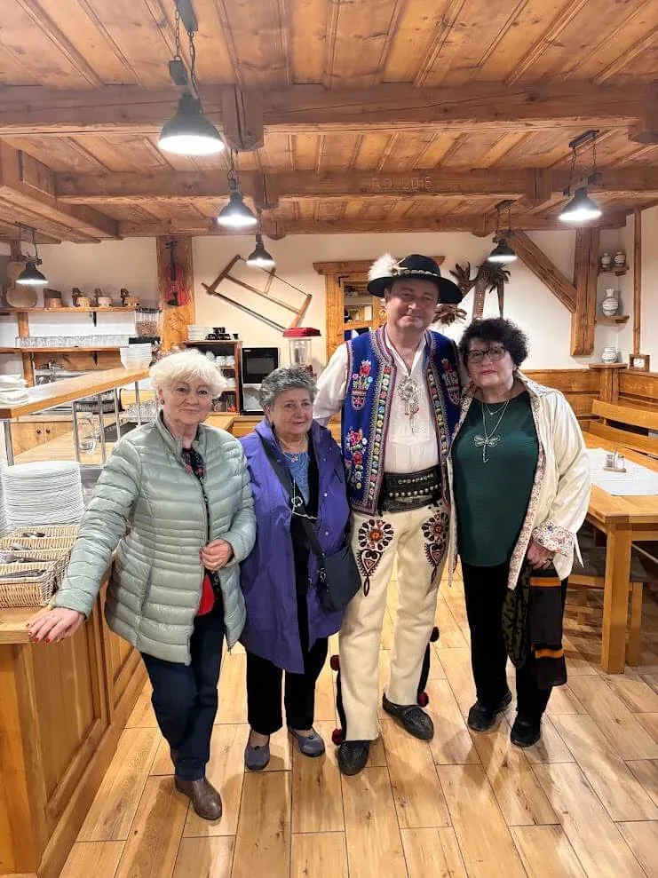 Three visitors with their host in full Slovak folk costume at a folk dinner in Stará Lesná.